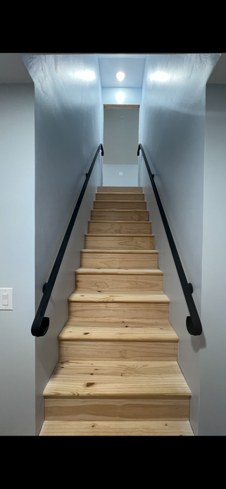 A simple hand rail going up a flight of stairs.